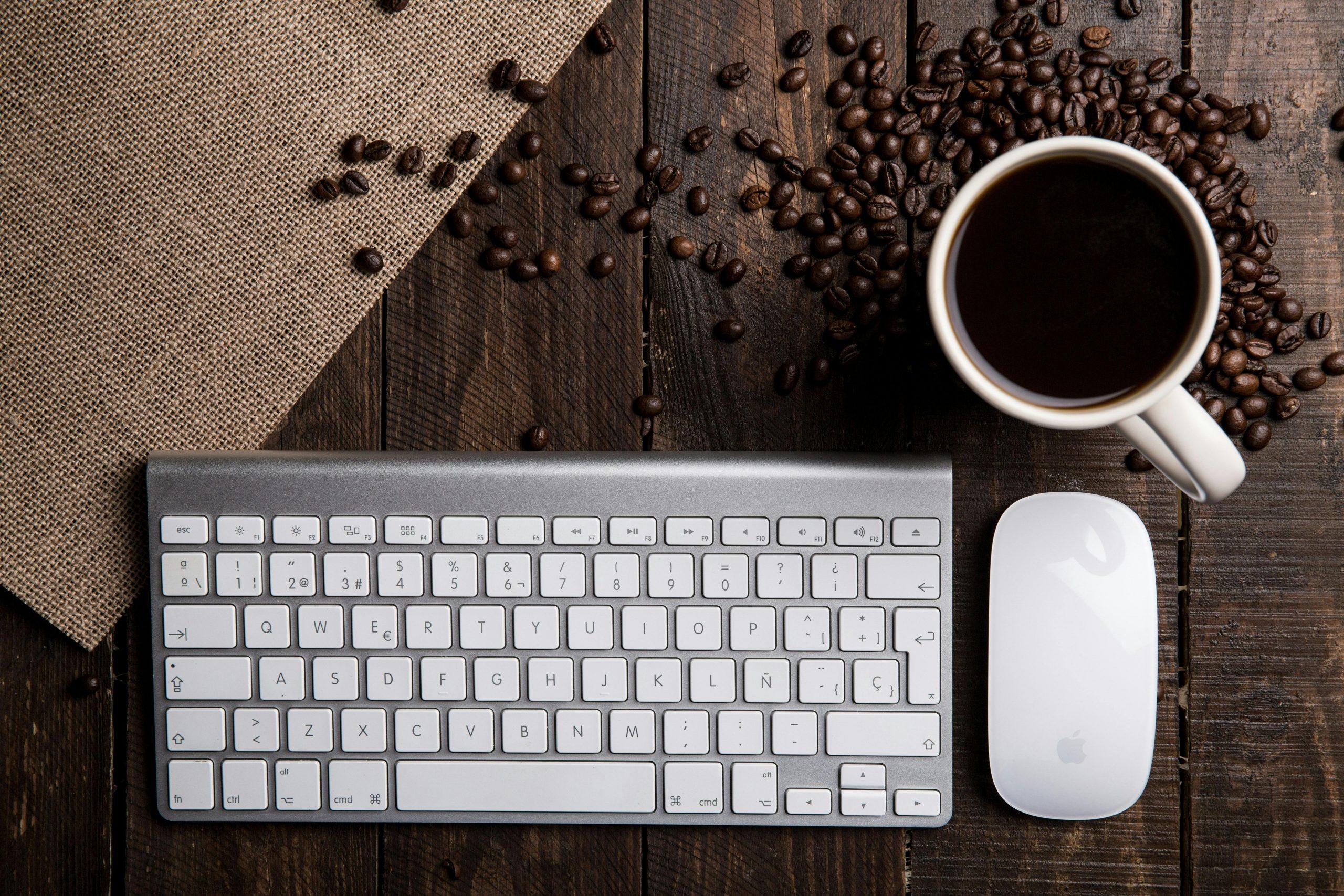 Top view of a coffee cup with keyboard and mouse on a rustic wooden desk.
